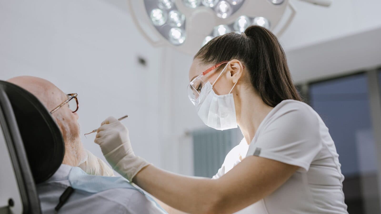 A dentist examining an older patient in a bright treatment room