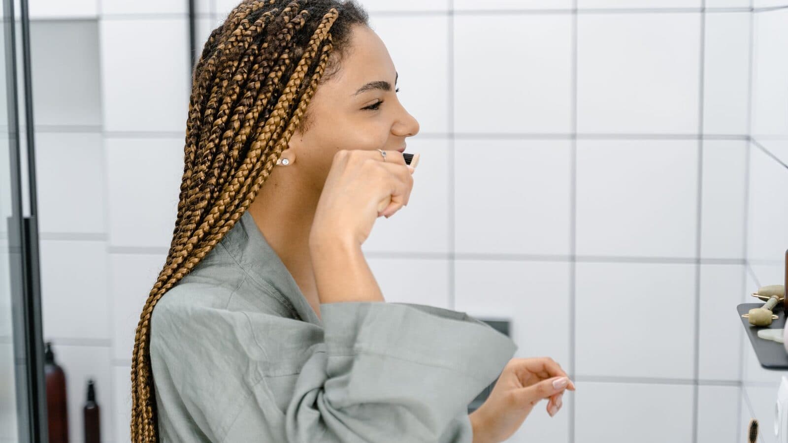 A woman with braided hair brushing her teeth, emphasizing daily oral hygiene and self-care.